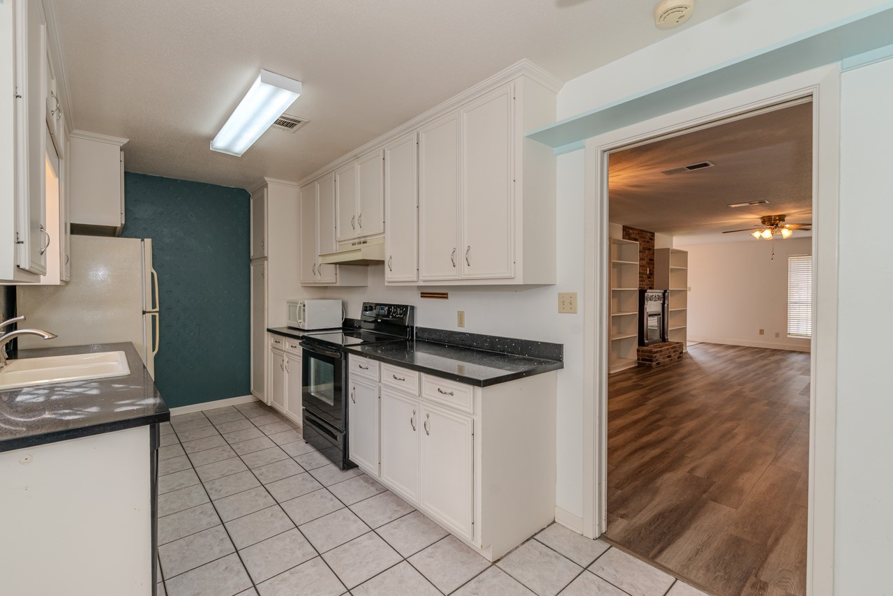 5975 Meadow Way Beaumont, TX 77707 - Photo 9 of 18 a kitchen with granite countertop a sink and a stove top oven