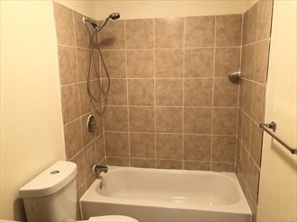 64 Tennis Plaza Road, Unit 2 Dracut, MA 01826 - Photo 8 of 11 a bath tub sitting next to a white toilet and a shower