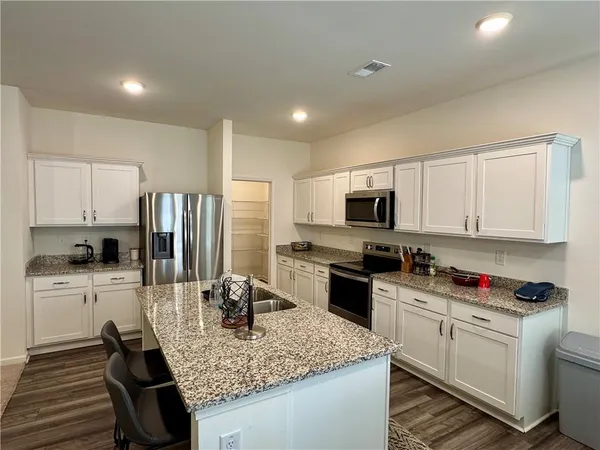 a kitchen with stainless steel appliances granite countertop a sink dishwasher stove refrigerator and cabinets with wooden floor