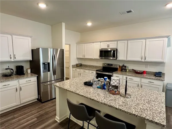 a kitchen with granite countertop a refrigerator stove top oven and sink