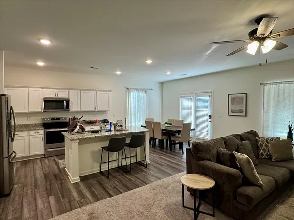 a living room with stainless steel appliances kitchen island furniture a kitchen view and a wooden floor