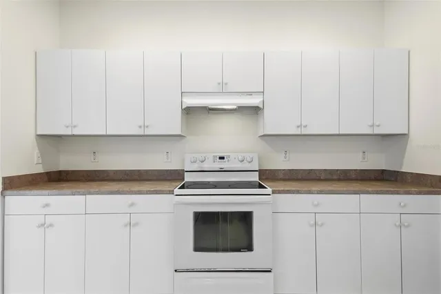 a kitchen with granite countertop white cabinets and white appliances