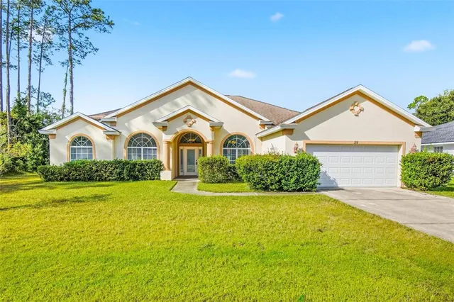 a view of a white house with a small yard and a large tree