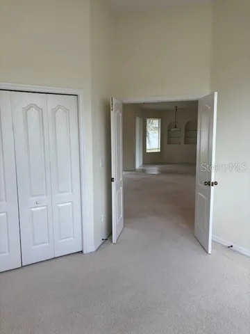 an empty room with windows and chandelier fan