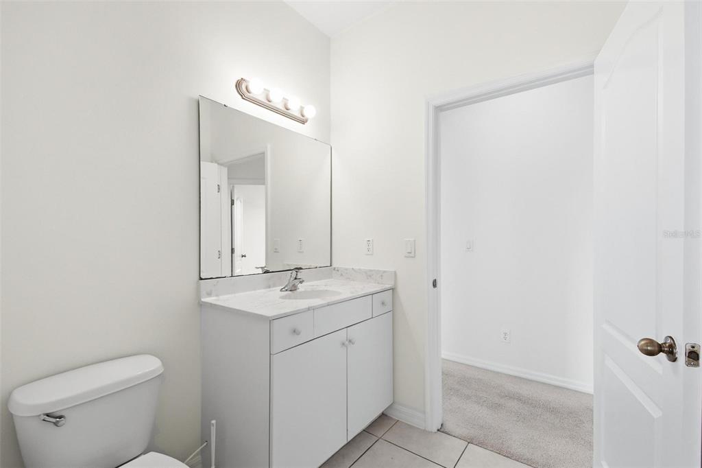 29 East Diamond Drive Palm Coast, FL 32164 - Photo 47 of 55 a bathroom with a granite countertop sink a toilet and a mirror