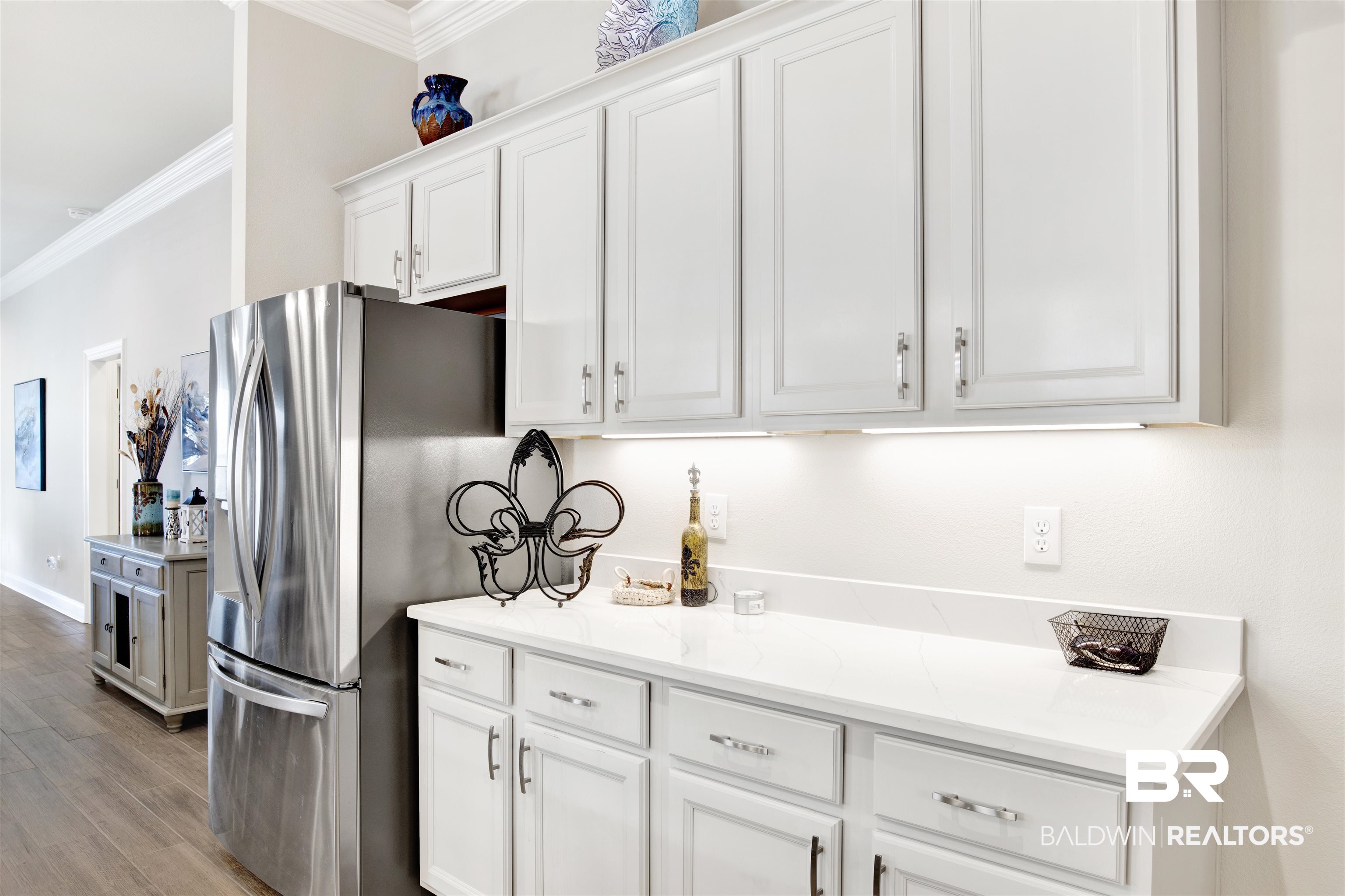 1406 Aldon Street Foley, AL 36535 - Photo 14 of 30 Kitchen featuring light gray cabinets, crown molding, luxury wood-look tile flooring, stainless steel fridge, and light Quartzsite counter tops.