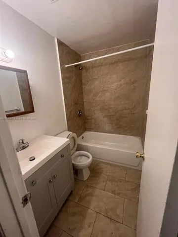 a bathroom with a granite countertop bathtub shower sink vanity and toilet