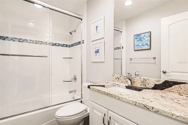 a bathroom with a granite countertop sink toilet and shower