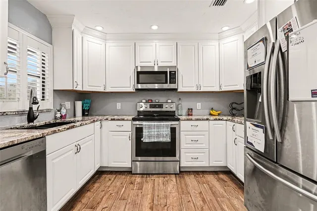 a kitchen with stainless steel appliances granite countertop a stove a sink and a refrigerator