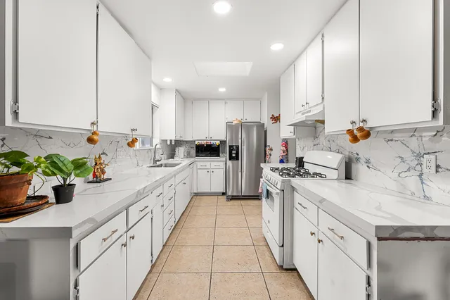 a kitchen with white cabinets and appliances