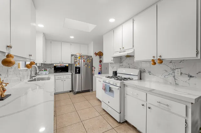 a kitchen with stainless steel appliances a stove a sink and white cabinets