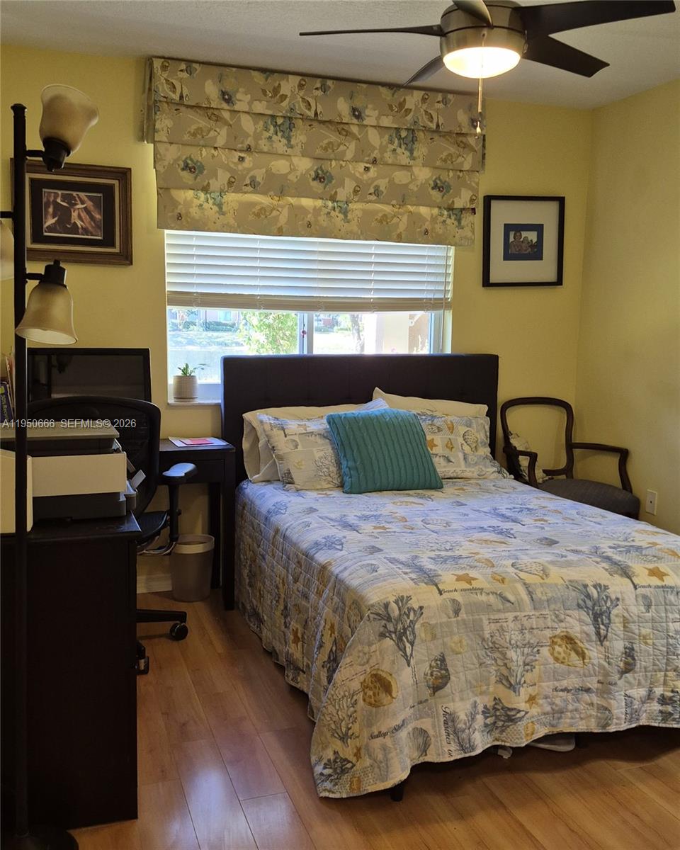 3854 Lyons Road, Unit 1025 Coconut Creek, FL 33073 - Photo 16 of 30 a bedroom with a bed and wooden floor