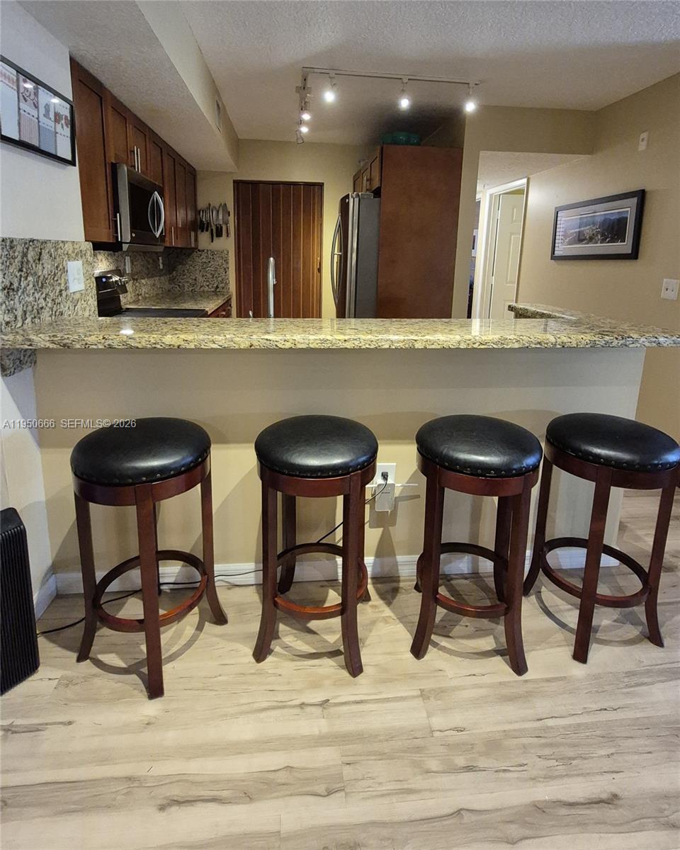 3854 Lyons Road, Unit 1025 Coconut Creek, FL 33073 - Photo 2 of 30 a kitchen with stainless steel appliances kitchen island granite countertop chairs and a refrigerator