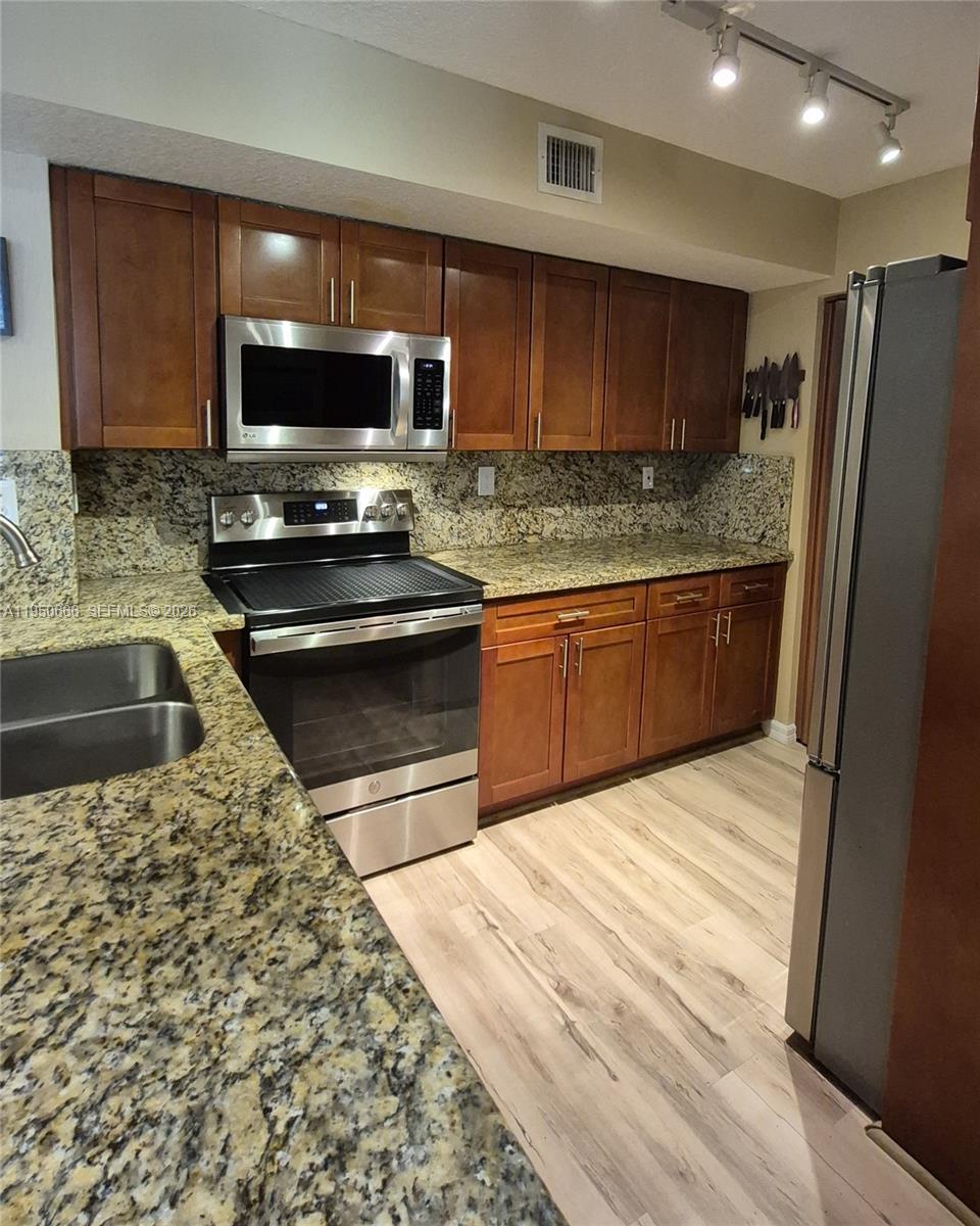 3854 Lyons Road, Unit 1025 Coconut Creek, FL 33073 - Photo 4 of 30 a kitchen with stainless steel appliances granite countertop a sink stove and microwave
