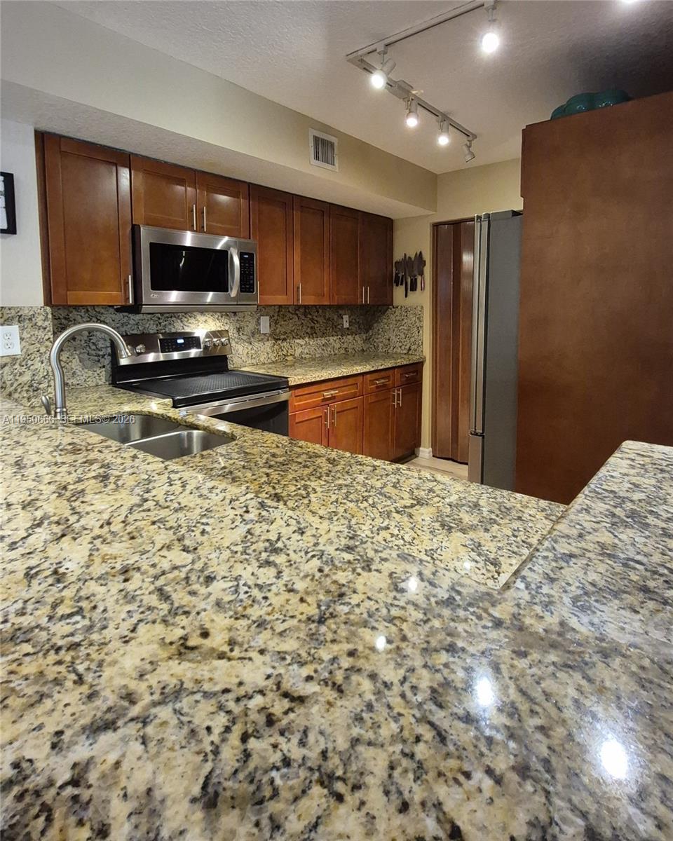 3854 Lyons Road, Unit 1025 Coconut Creek, FL 33073 - Photo 5 of 30 a kitchen with granite countertop a refrigerator stove microwave and sink