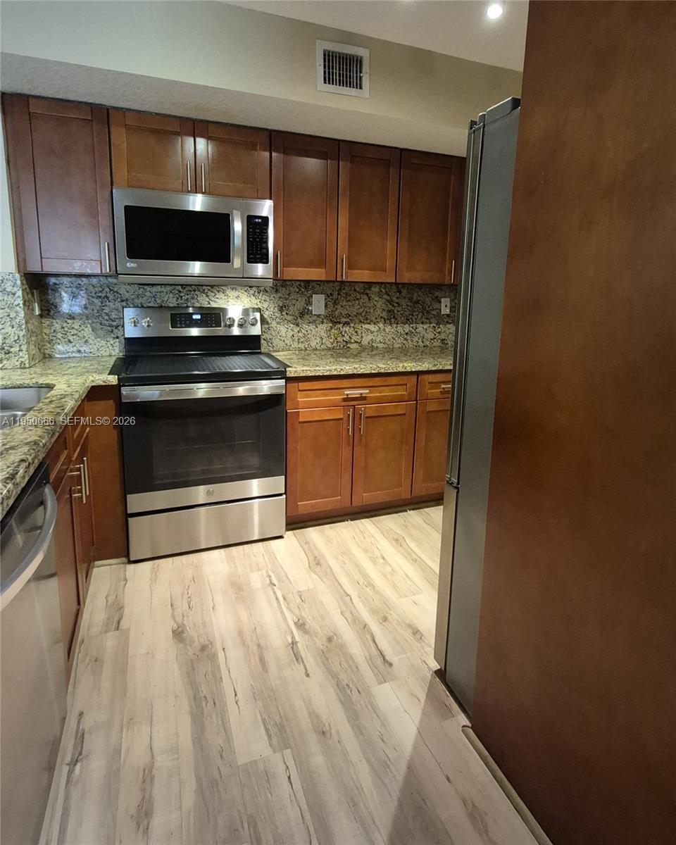 3854 Lyons Road, Unit 1025 Coconut Creek, FL 33073 - Photo 6 of 30 a kitchen with granite countertop a stove and a microwave