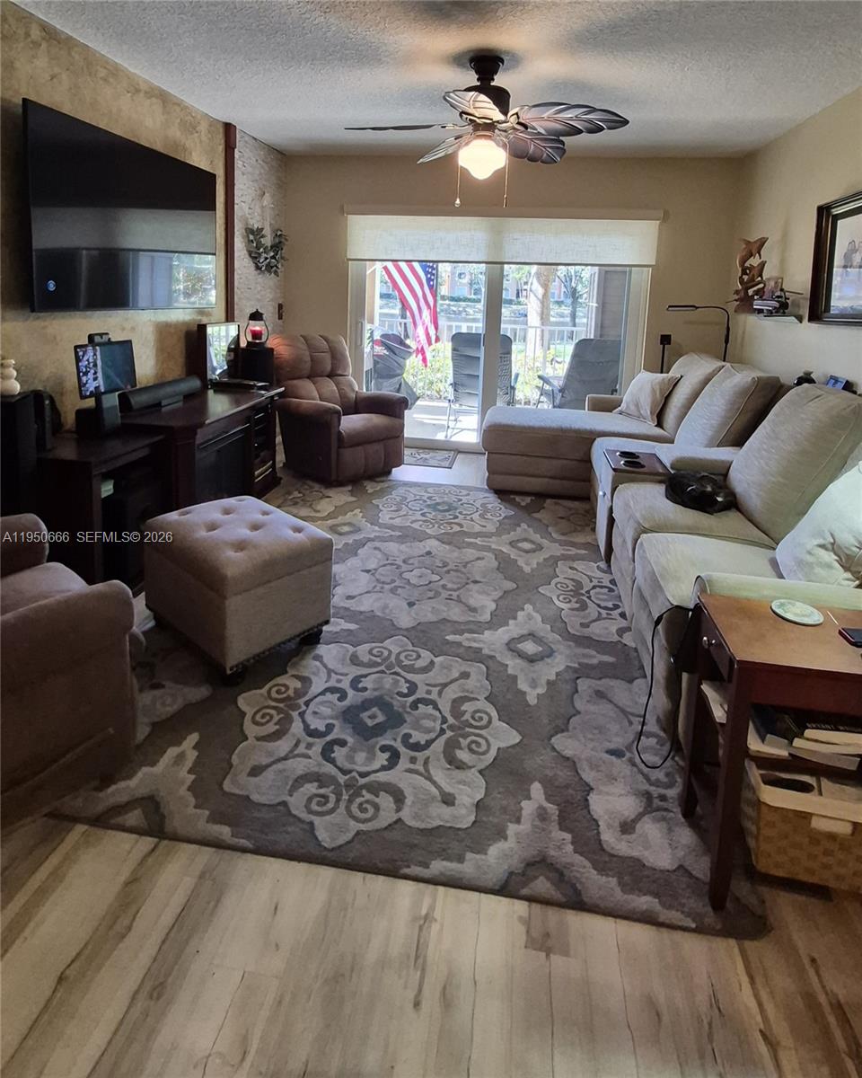 3854 Lyons Road, Unit 1025 Coconut Creek, FL 33073 - Photo 7 of 30 a living room with furniture a flat screen tv and a window