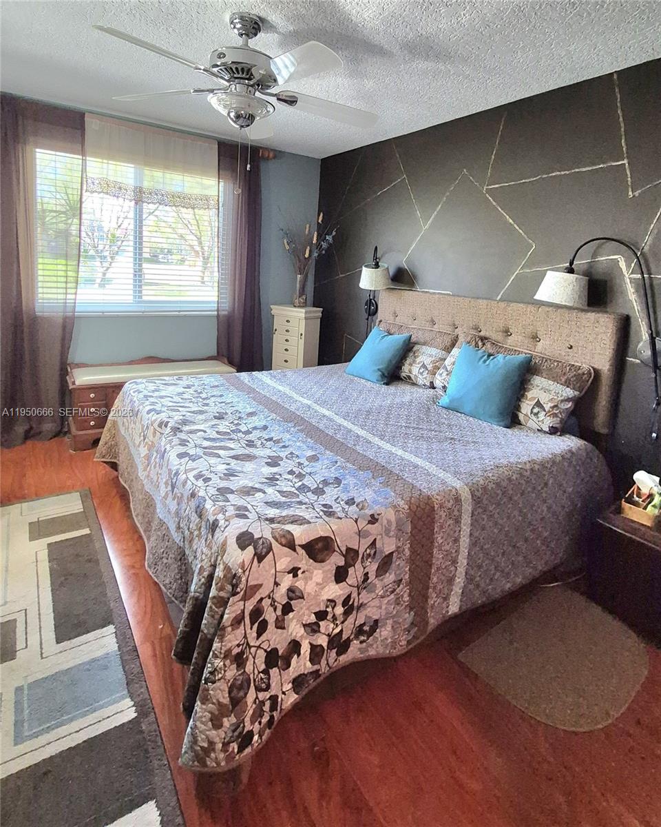 3854 Lyons Road, Unit 1025 Coconut Creek, FL 33073 - Photo 9 of 30 a bedroom with a large bed and a chandelier