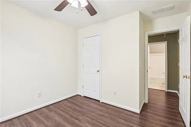 an empty room with wooden floor cabinet and windows