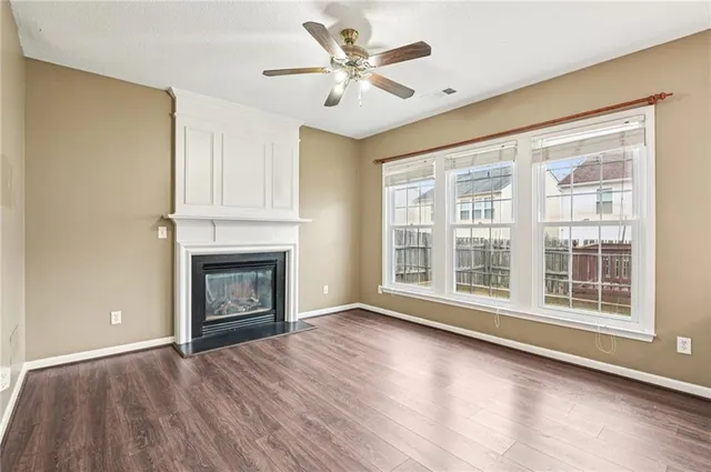 a view of a livingroom with a fireplace a ceiling fan and windows