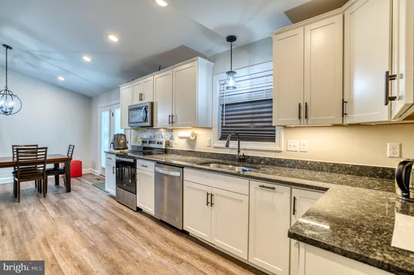 a kitchen with stainless steel appliances granite countertop a stove a sink and white cabinets