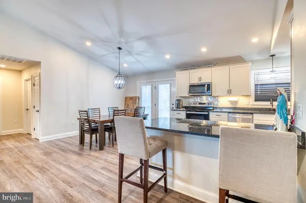 a kitchen view with stainless steel appliances granite countertop a stove a refrigerator a kitchen island a table and chairs with wooden floor