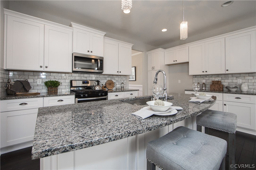 8955 Lavenham Loop Midlothian, VA 23112 - Photo 15 of 47 a kitchen with stainless steel appliances granite countertop a sink stove and cabinets