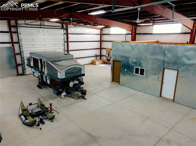 940 Puma Hills Road Lake George, CO 80827 - Photo 23 of 42 Spacious warehouse interior featuring a large roll-up door, exposed metal beam construction, and a concrete floor