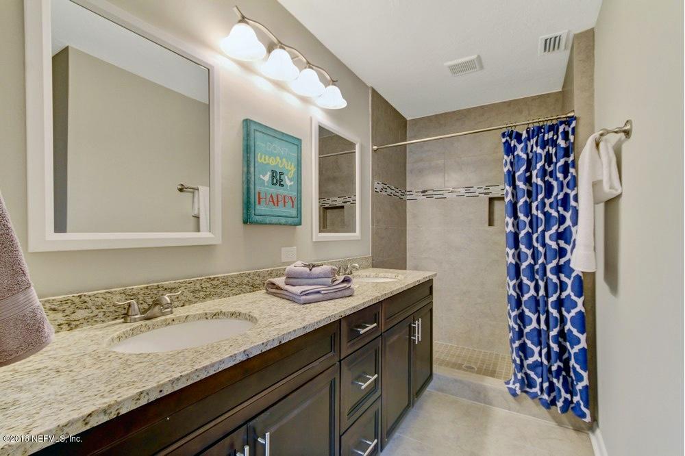 6815 Heidi Road Jacksonville, FL 32277 - Photo 24 of 36 a bathroom with a granite countertop sink a mirror a vanity and shower