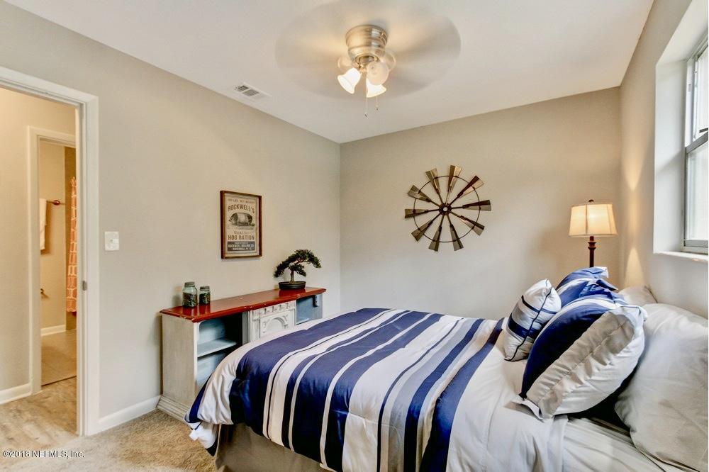 6815 Heidi Road Jacksonville, FL 32277 - Photo 26 of 36 a bedroom with a bed and a chandelier