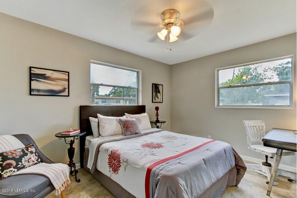 6815 Heidi Road Jacksonville, FL 32277 - Photo 27 of 36 a bedroom with a bed and a chandelier