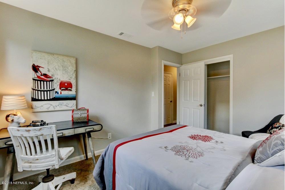 6815 Heidi Road Jacksonville, FL 32277 - Photo 28 of 36 a bedroom with a bed and a chandelier