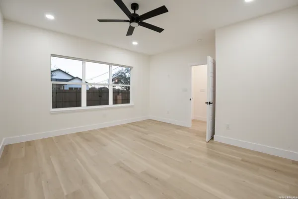 an empty room with wooden floor fan and windows