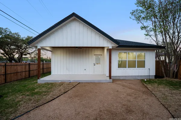 a view of backyard with large tree and wooden fence