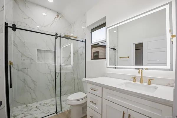 a bathroom with a shower sink vanity mirror and toilet