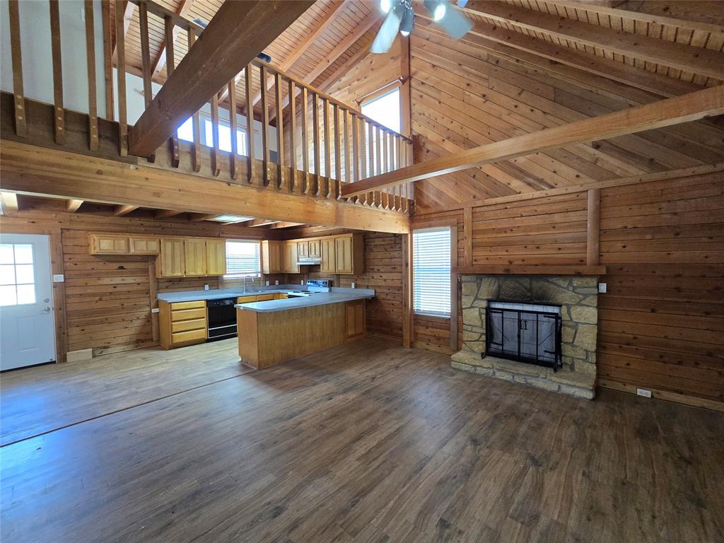 3505 Farmer Road Azle, TX 76020 - Photo 4 of 40 Downstairs living room has a stone fireplace, a ceiling fan and decorative lighting. New window blinds and wood-look flooring installed in most areas summer 2026!