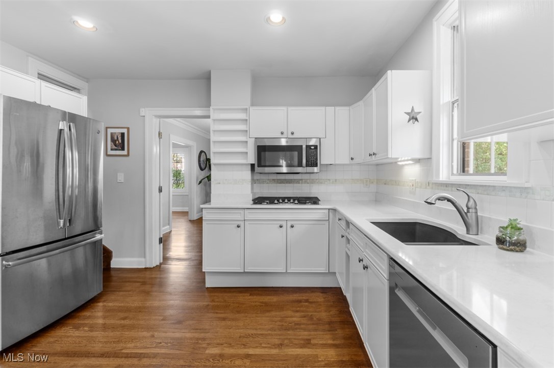 3124 Warrington Road Cleveland, OH 44120 - Photo 12 of 36 Kitchen featuring tasteful backsplash, a sink, white cabinetry, dark wood finished floors, and appliances with stainless steel finishes