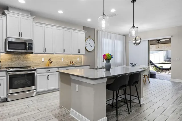 a kitchen with granite countertop a stove a sink a dining table and chairs with wooden floor