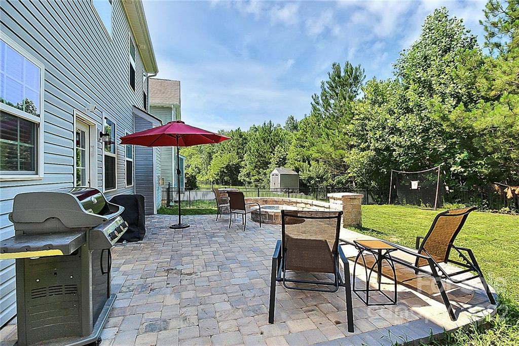 78134 Rillstone Drive Lancaster, SC 29720 - Photo 5 of 26 a view of a patio with a dining table and chairs under an umbrella with barbeque grill and wooden fence