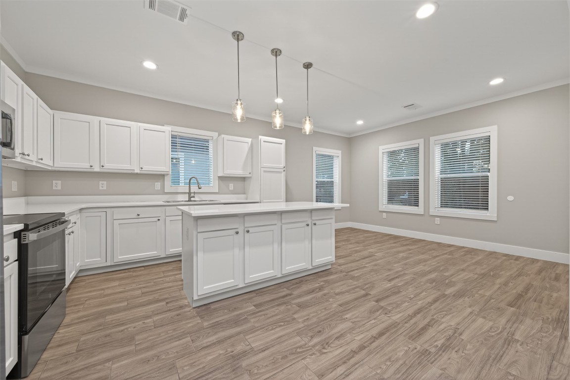 6605 Greenhurst Street Houston, TX 77091 - Photo 4 of 41 a large kitchen with stainless steel appliances granite countertop a stove a sink dishwasher a refrigerator white cabinets and wooden floor next to a window