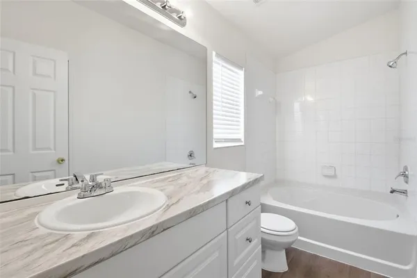 a bathroom with a granite countertop sink a toilet and bathtub
