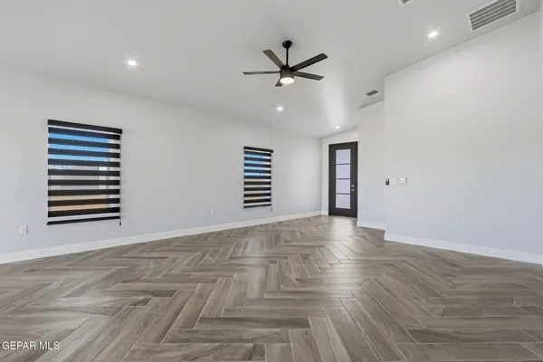 a view of empty room with wooden floor and ceiling fan