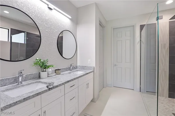 a bathroom with a granite countertop double vanity sink and a mirror