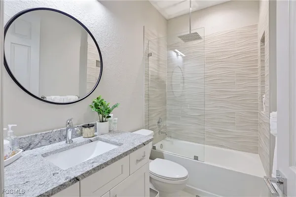 a bathroom with a granite countertop sink a toilet and a mirror