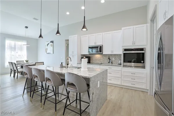 a kitchen with stainless steel appliances a table chairs refrigerator and microwave