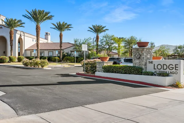 a front view of multi story residential apartment building with yard and bench