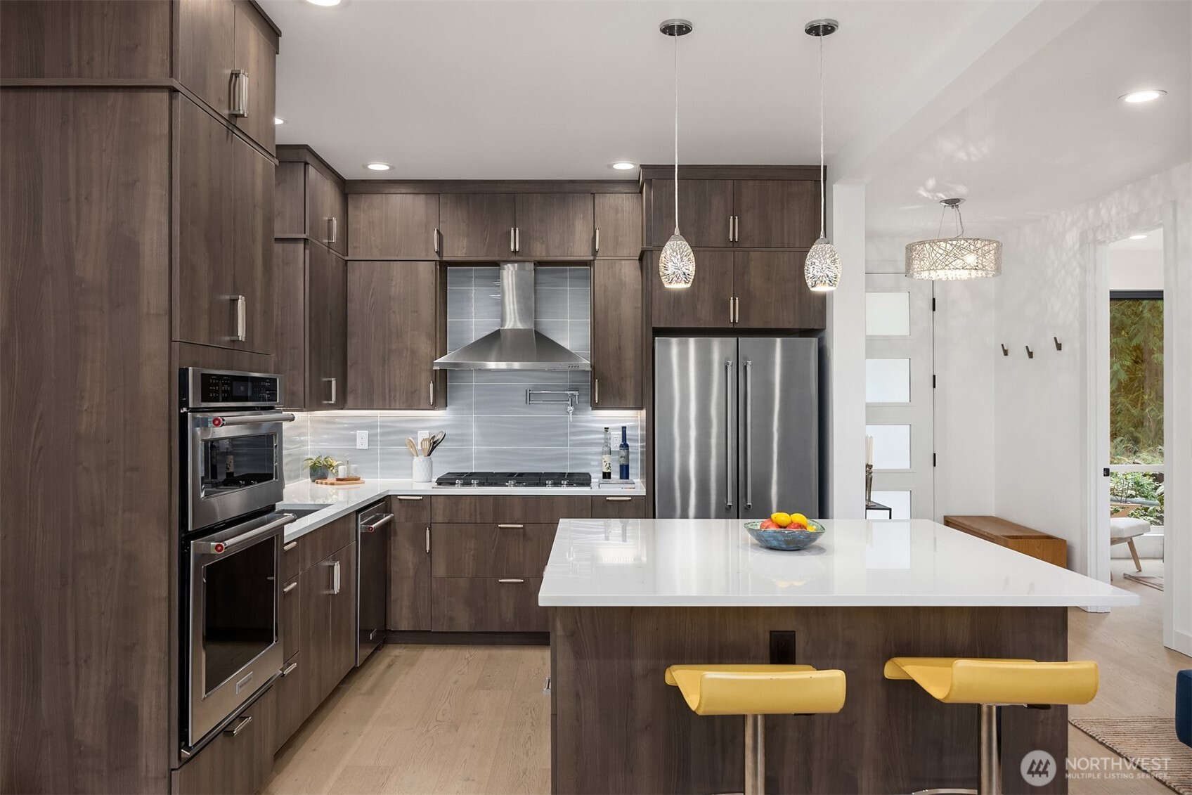 13532 Phelps Road Northeast Bainbridge Island, WA 98110 - Photo 11 of 35 a kitchen with stainless steel appliances kitchen island a table chairs in it and wooden floors