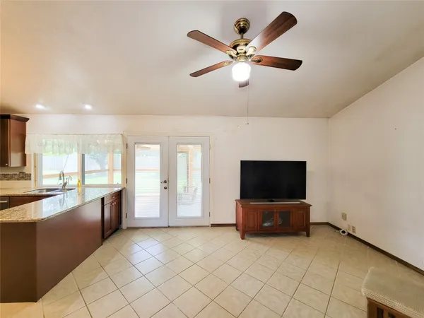 an empty room with wooden floor chandelier fan and windows