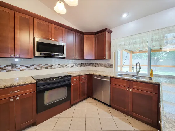 a large kitchen with stainless steel appliances kitchen island granite countertop a refrigerator and a stove top oven
