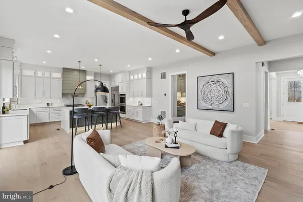 a kitchen with kitchen island granite countertop a sink a stove a refrigerator and white cabinets with wooden floor